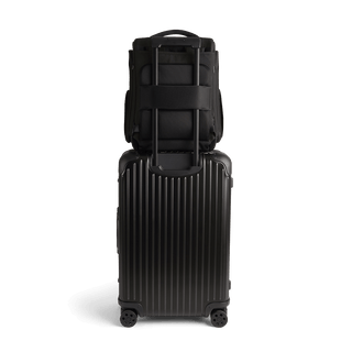 A Kamella Pet Backpack and Car Seat, in onyx, from the back attached to a suitcase using the trolley sleeve